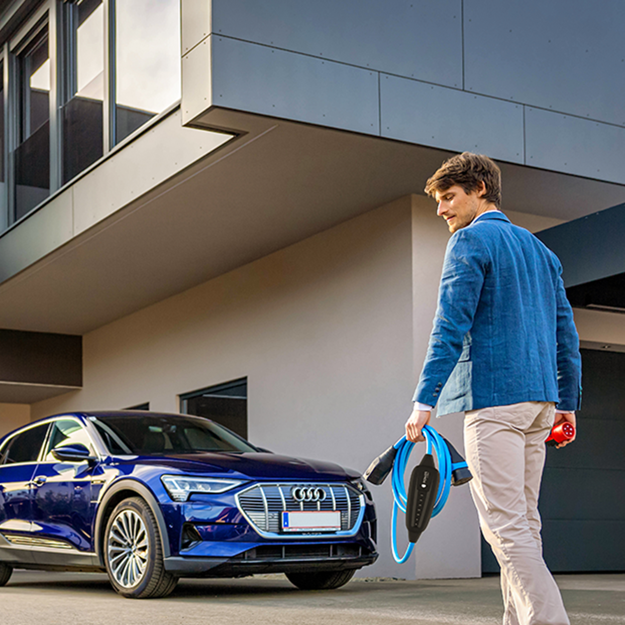 Person walks towards an electric car with cable in hand